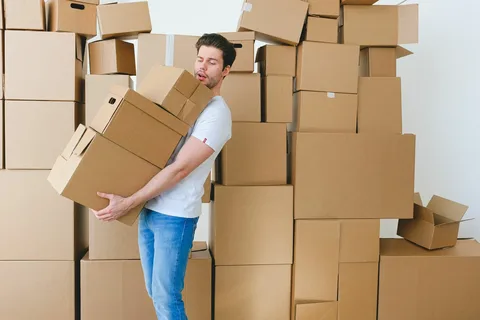 Professional movers carefully packing belongings into boxes for relocation. Text: Trusted movers and packers in Sharjah offering expert relocation services tailored to your needs.